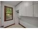 Functional laundry room with ample cabinet space, a window, and tile flooring at 100 Hartford Pl, Fayetteville, GA 30214