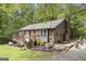 Back of brick home with wooden deck surrounded by mature trees and landscaping at 165 White Rose Ln, Temple, GA 30179