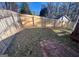 A fenced-in backyard, partially overgrown with a small stone patio visible at 3875 Grand Prix St, Cumming, GA 30041