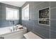 A renovated bathroom with a soaking tub and gray tile at 3979 Doral Cir, Atlanta, GA 30360