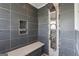 Walk-in shower features gray tiling, a built-in seat, and shelving at 3979 Doral Cir, Atlanta, GA 30360