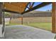 Spacious stone patio with a wood-beamed ceiling, overlooking a manicured backyard and retaining wall at 1240 Hayes Sq, Peachtree City, GA 30269