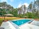Backyard swimming pool with shaded seating and lush landscaping, perfect for outdoor enjoyment and entertaining at 106 Tullamore Trl, Tyrone, GA 30290