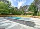 Beautiful backyard pool with stone accents, surrounded by lush greenery and shaded seating areas for relaxation at 106 Tullamore Trl, Tyrone, GA 30290