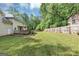 Large grassy backyard featuring a wooden deck, lush greenery, and secure fencing for privacy at 5045 Rock Springs Rd, Lithonia, GA 30038
