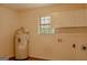 Bright laundry room featuring a window, white cabinets and a water heater at 7017 Sun Valley Way, Riverdale, GA 30274