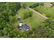 An aerial view of a home nestled among trees and open land showcases a long driveway at 333 Old Carrollton Rd, Roopville, GA 30170