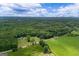 Beautiful aerial shot of wooded property with fields, sky, and a beautiful home nestled in the trees at 333 Old Carrollton Rd, Roopville, GA 30170