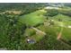 Aerial view showcases a residence nestled amongst mature trees, adjacent fields, and a neighboring poultry farm at 333 Old Carrollton Rd, Roopville, GA 30170