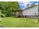 View of home's backyard and back porch, surrounded by lush green lawn and trees at 333 Old Carrollton Rd, Roopville, GA 30170