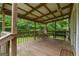 Relaxing covered porch featuring wood floors, beamed ceiling, and peaceful wooded views at 333 Old Carrollton Rd, Roopville, GA 30170