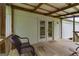 Inviting covered porch with wood floors, door access to interior, and wooded views at 333 Old Carrollton Rd, Roopville, GA 30170