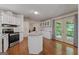 Bright kitchen boasts white cabinets, island, hardwood floors, and backyard access at 333 Old Carrollton Rd, Roopville, GA 30170