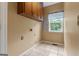 Functional laundry area with overhead cabinet, window and tile floor at 333 Old Carrollton Rd, Roopville, GA 30170