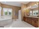 Bright main bathroom featuring a soaking tub, tiled floors, double sinks and wood vanity at 333 Old Carrollton Rd, Roopville, GA 30170