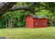 Red outbuilding on a well-maintained lawn with lush greenery and a black roof at 333 Old Carrollton Rd, Roopville, GA 30170