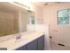 Bright bathroom with a blue vanity, white marble countertop, and a large mirror at 5851 Giles Rd, Lithonia, GA 30058