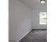 Empty bedroom with gray carpet, white walls, and a window overlooking the neighborhood at 5851 Giles Rd, Lithonia, GA 30058
