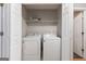 Brightly lit laundry closet with a white washer, dryer, and storage shelf at 1360 Maple Valley Ct, Union City, GA 30291
