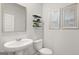 A bright half bath features a pedestal sink, toilet, and modern artwork at 326 Sound Cir # 119, Stockbridge, GA 30281