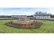 Landscaped entrance featuring a stone fountain with colorful flowers in front of newly built townhomes under a blue sky at 334 Sound Cir, Stockbridge, GA 30281