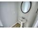 Powder room features a pedestal sink, oval mirror, and light wood flooring at 695 Park Place Way, Social Circle, GA 30025