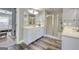 Bright bathroom with dual sinks, glass enclosed shower, and dark hardwood floors at 5845 Princeton Run Trl, Tucker, GA 30084