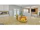 Kitchen island with granite countertop and a bowl of fruit; view into the living room at 5845 Princeton Run Trl, Tucker, GA 30084