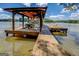Covered wooden boat dock featuring a boat lift and a relaxing seating area, set against calm lake waters at 2000 Campbell Rd, Covington, GA 30014