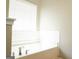 Clean white bathtub surrounded by white tiled walls and featuring a window for natural light at 65 Heaton Place Trl, Covington, GA 30016