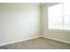 A serene empty bedroom with neutral carpet, freshly painted walls, and a bright window at 65 Heaton Place Trl, Covington, GA 30016