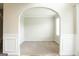 Bright, empty living room featuring neutral walls, carpet, and an arched doorway at 65 Heaton Place Trl, Covington, GA 30016
