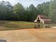 A rustic wooden barn with a red roof sits nestled on a large lot with mature trees at 1685 Bailey Creek Sw Rd, Conyers, GA 30094