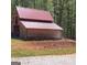 The two-story barn boasts a pristine red roof and wood exterior at 1685 Bailey Creek Sw Rd, Conyers, GA 30094
