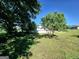 A grassy backyard featuring mature trees offering shade, with a partial view of the house at 140 Whitehead Sw Rd, Oxford, GA 30054