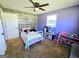 A colorful bedroom with a white bed, wooden-look accent wall, and ceiling fan for comfortable living at 140 Whitehead Sw Rd, Oxford, GA 30054