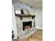 Close up of a stone fireplace with a wood mantle and decorative items on the mantel at 140 Whitehead Sw Rd, Oxford, GA 30054