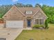 Charming single-Gathering home with brick and stone accents, a manicured lawn, and an attached two-car garage at 228 Madison Grace Ave, Mcdonough, GA 30252