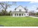 Backyard view of a spacious yard, covered porch, and white farmhouse-style home with mature trees at 61 Main St, Moreland, GA 30259