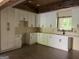 Bright kitchen featuring white cabinets with black hardware, wood ceiling beams, and a window over the sink at 135 Church St, Palmetto, GA 30268