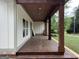 Inviting covered front porch with wood floors and ceiling plus decorative columns at 135 Church St, Palmetto, GA 30268
