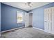 Blue bedroom with a neutral carpet, ceiling fan, and view from the window at 231 Breckenridge Ln, Powder Springs, GA 30127
