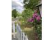 View of the front yard featuring a white picket fence and flowering bushes along the driveway at 854 Clearwater Rd, Sharpsburg, GA 30277