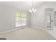 Sunlit dining area featuring a modern chandelier and large window, complemented by neutral carpet at 40 Kelsey Way, Palmetto, GA 30268