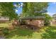Backyard featuring a brick house, a wooden porch, a patio area, and mature trees, offering a tranquil outdoor space at 235 Castlegate Cir, Carrollton, GA 30116