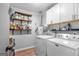 Functional laundry room with washer, dryer, storage shelving, and laminate flooring at 235 Castlegate Cir, Carrollton, GA 30116