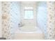 Bright bathroom featuring a built-in tub beneath a window, and floral wallpaper at 260 Emerald Lake Dr, Fayetteville, GA 30215