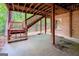 Covered patio area with brick exterior, stairs leading to the backyard, and forest views at 260 Emerald Lake Dr, Fayetteville, GA 30215
