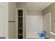 Bathroom featuring white bathtub with shower and storage space with an open shelving unit at 5998 Radford Dr, Riverdale, GA 30296