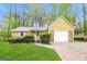 Charming home with a yellow exterior, stone accents, attached garage and green lawn at 5998 Radford Dr, Riverdale, GA 30296